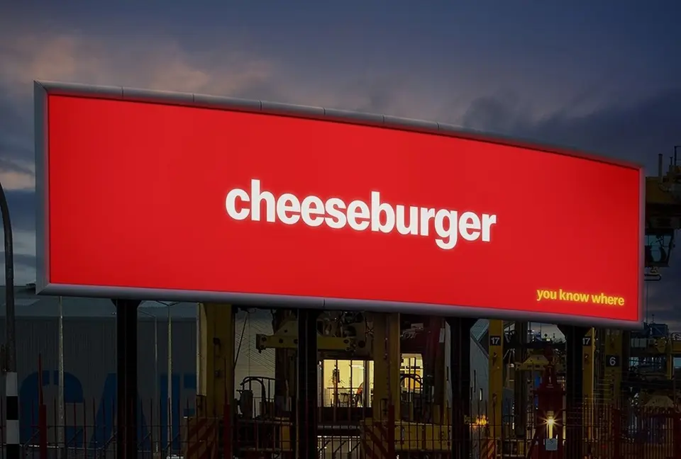Red billboard reading “cheeseburger — you know where”, with no logo